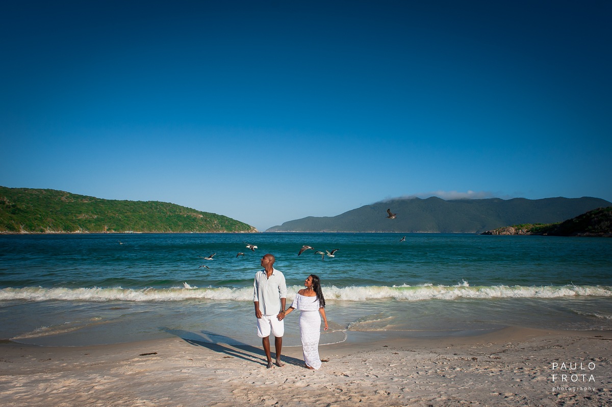 casal na praia do forno, com pássaros voando.