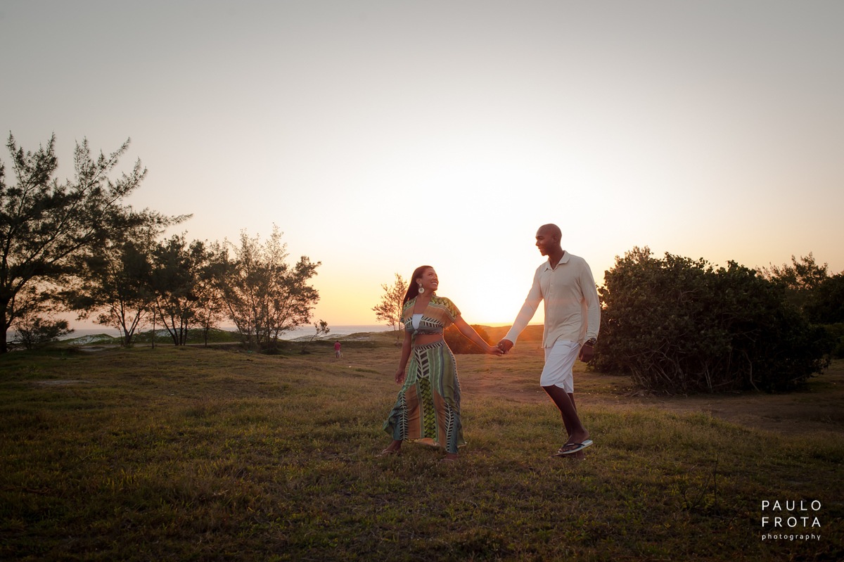 casal andando no gramado, sol atrás