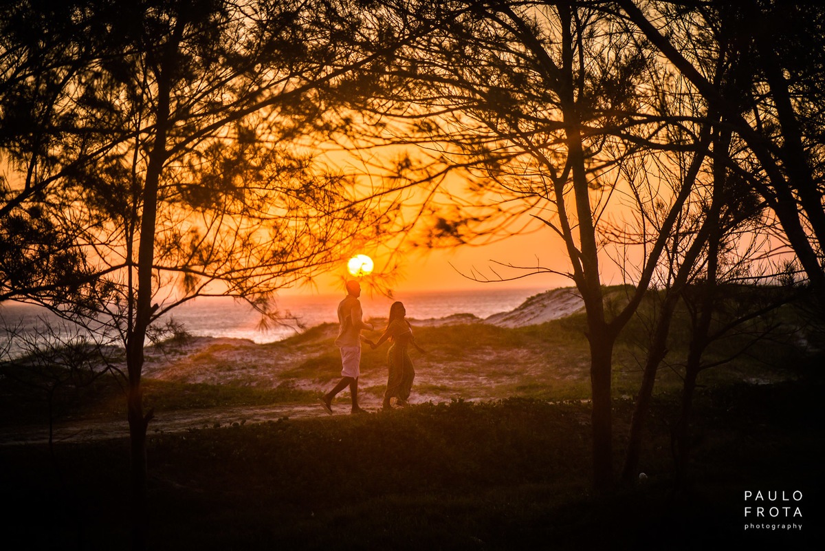 casal andando no gramado, sol atrás