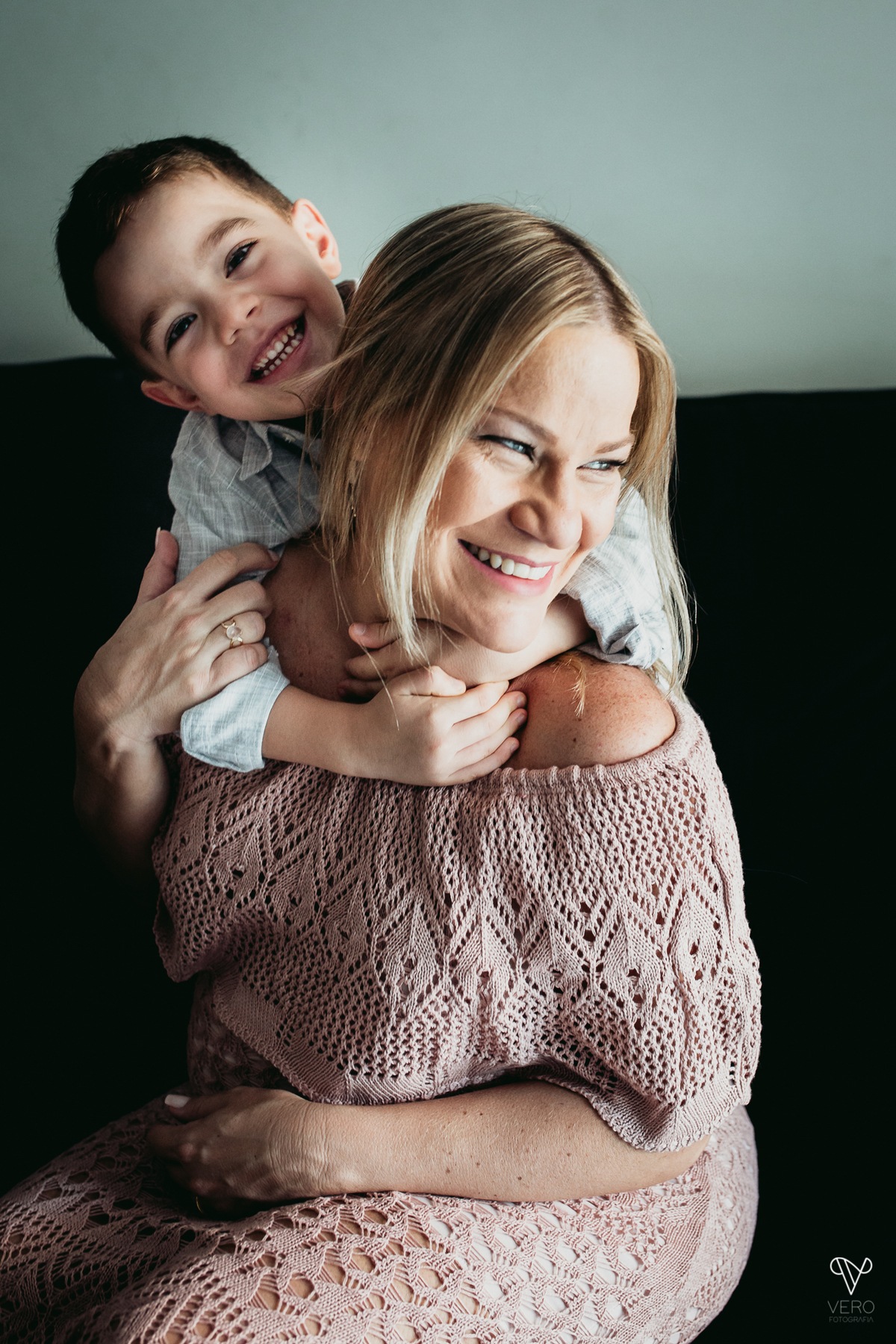 Filho abraça a mãe gestante no sofá
