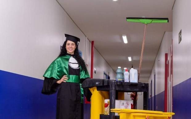 Zeladora posa para fotos de formatura com materiais de limpeza