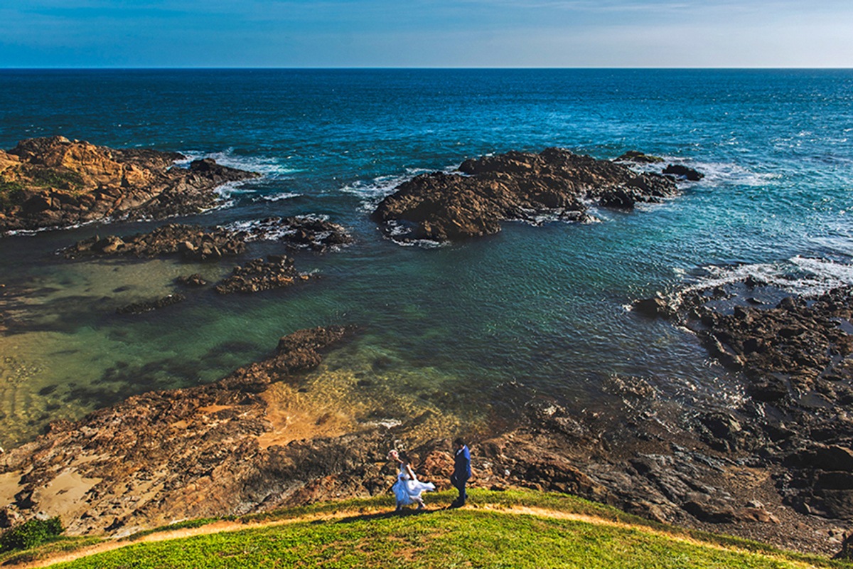 Foto no ensaio de pós casamento na Bahia em Salvador com casal passeando atrás do farol da Barra e com vista pro mar