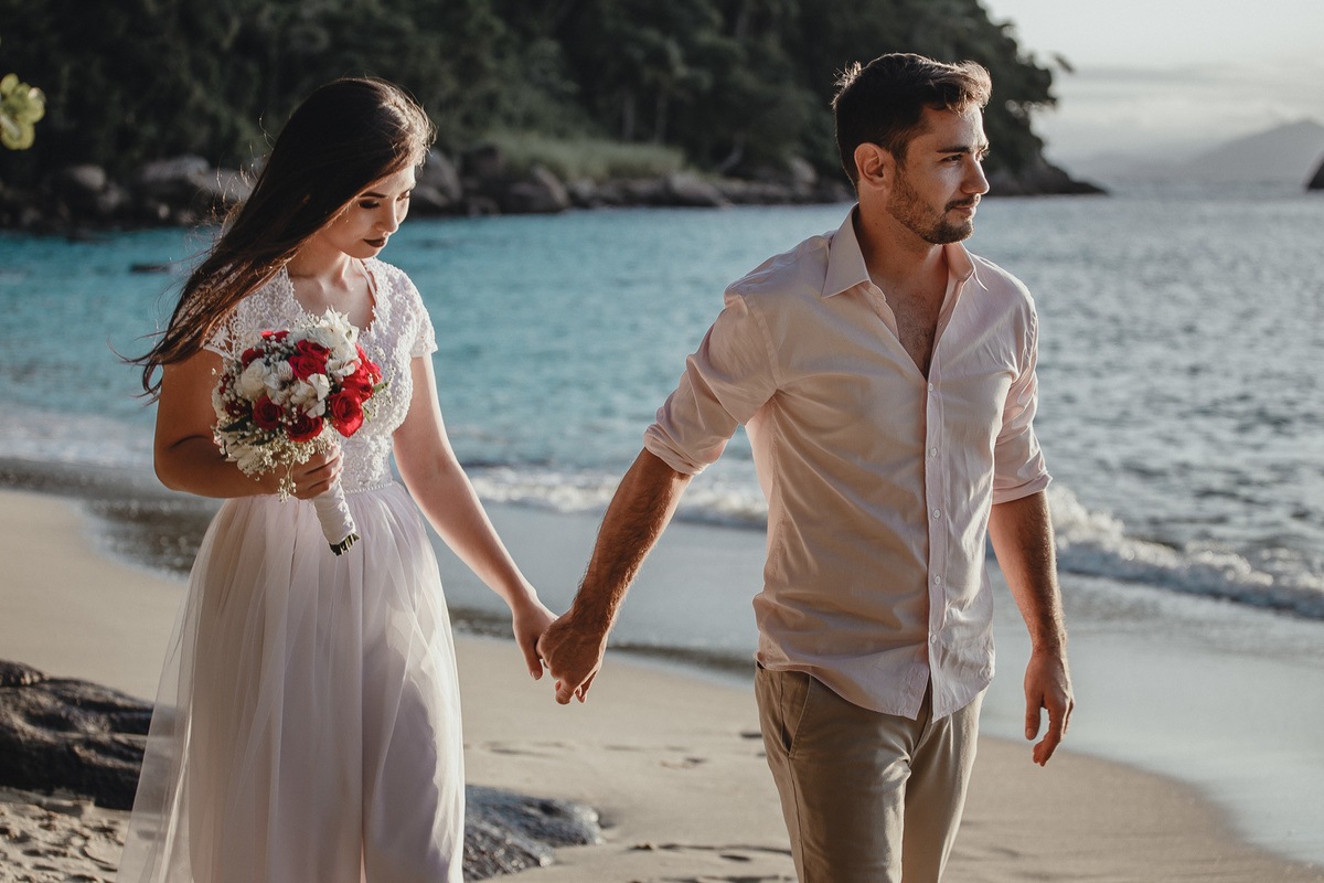 Casal apaixonado e lindo caminhando de mãos dadas na areia da praia