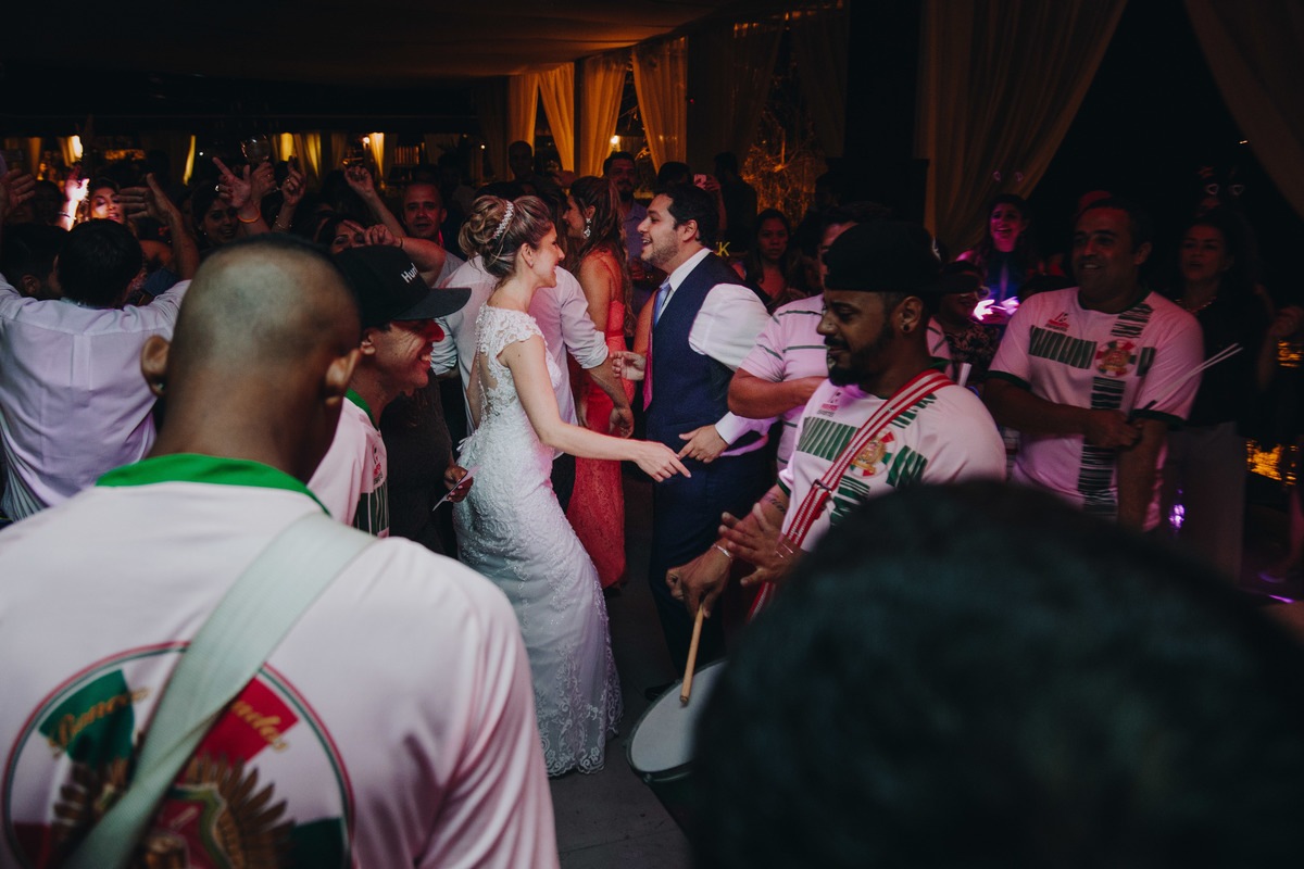 Noivos felizes e apaixonados dançando com a bateria da escola de samba na festa do casamento