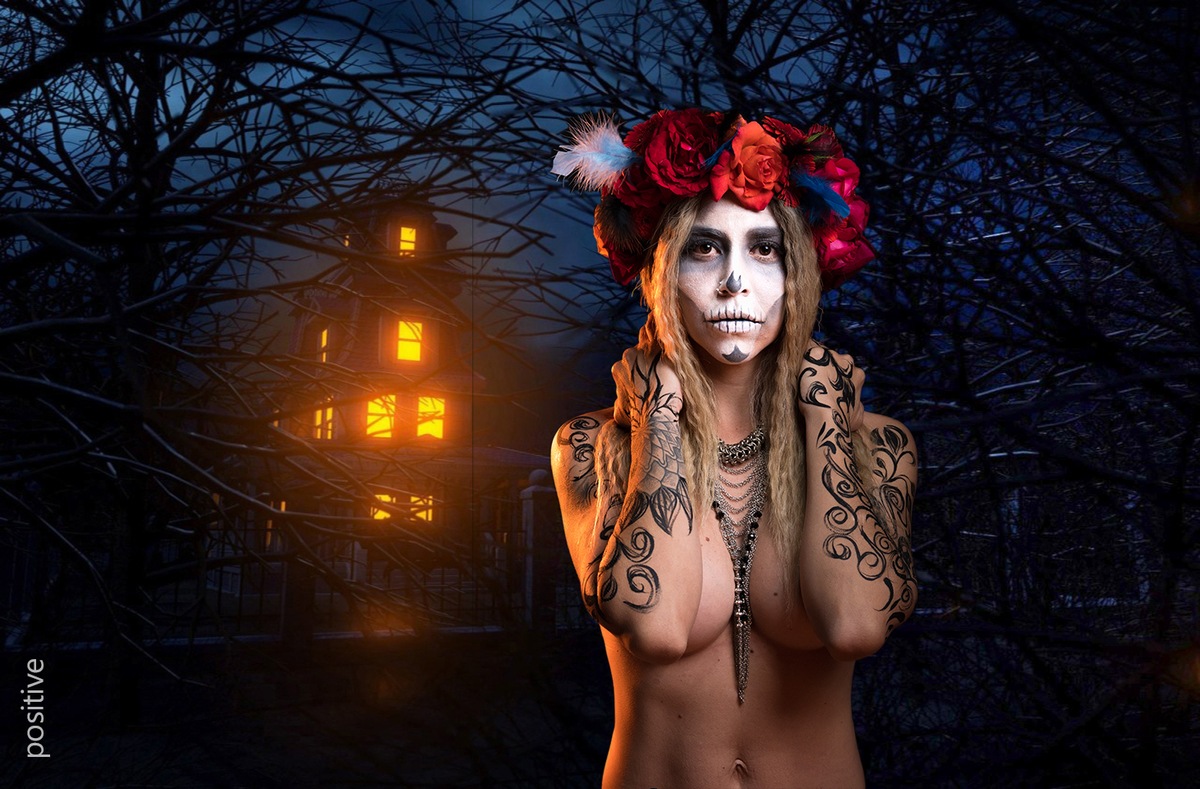 Catrina de noche con casa iluminada detrás de ella