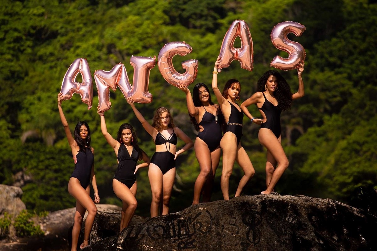 grupo de meninas segurando balões com a palavra amigas.