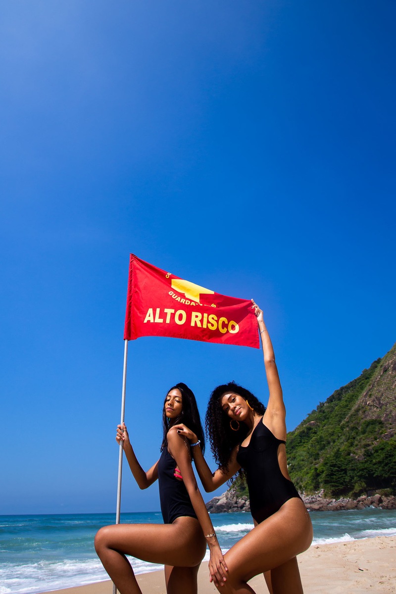duas meninas segurando a bandeira de alto risco do mar na praia