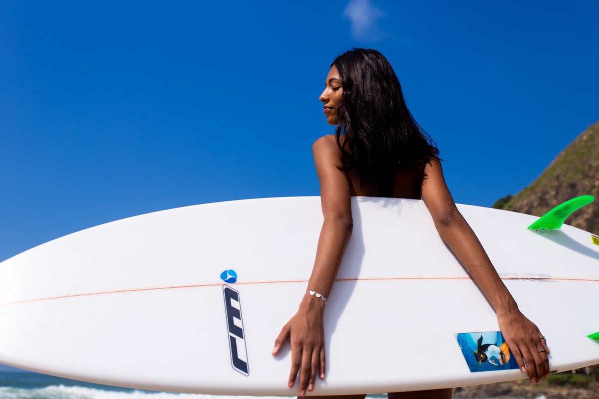 menina segurado prancha de surf na praia.
