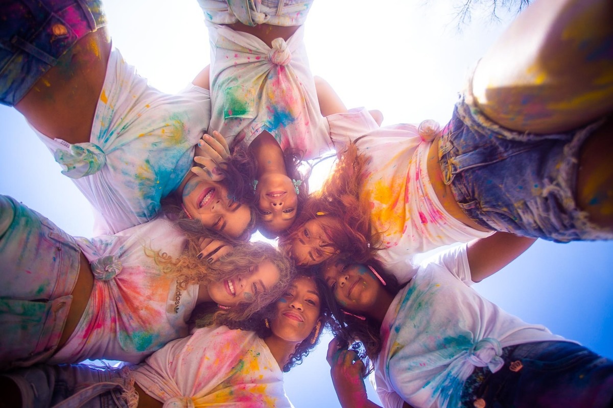 grupo de 6 meninas abraçadas e com roupas manchadas posando pra foto.