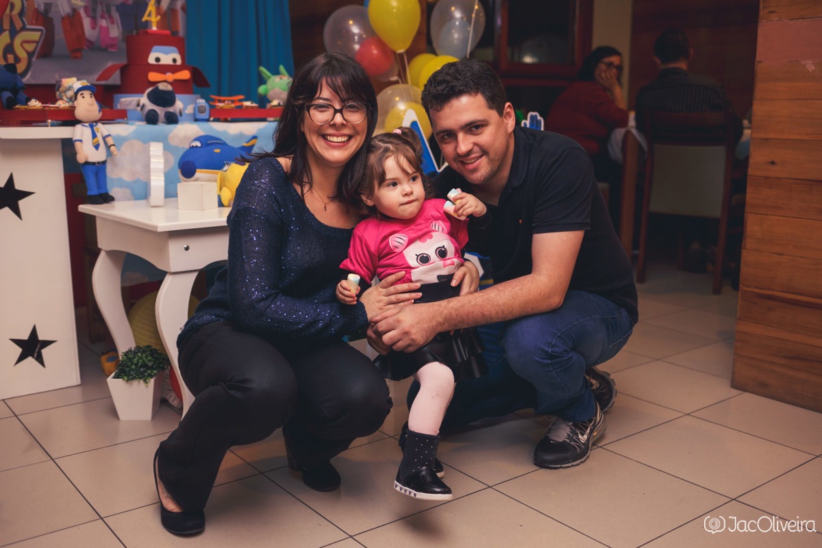 pais e filha posando em frente a mesa do bolo aniversário super wings