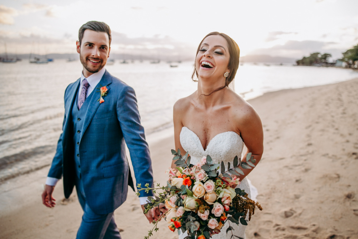 casal caminhando na praia com bouquet de flores