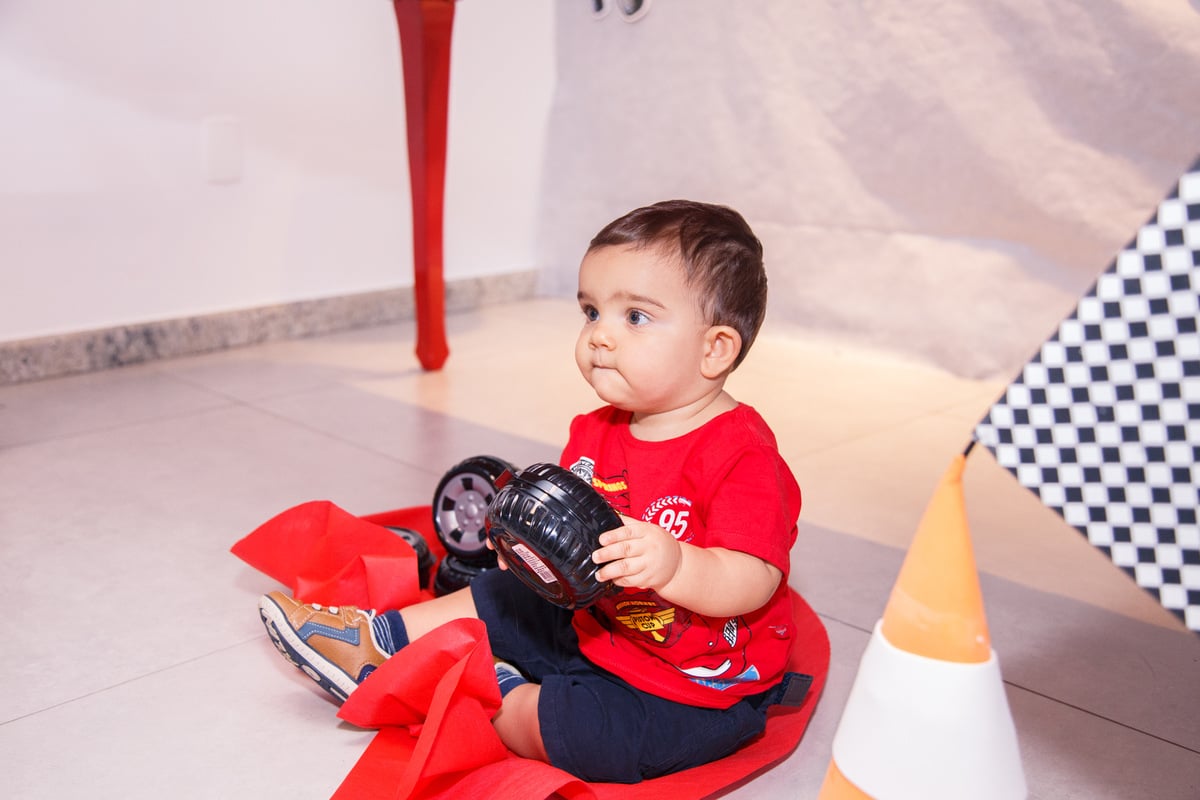 Criança brincando no chão com carrinhos durante seu aniversário de 1 ano no tema Carros.