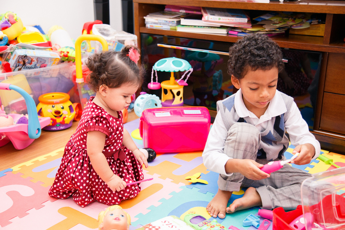 Duas crianças brincando no quarto de brinquedo durante um aniversário infantil intimista.