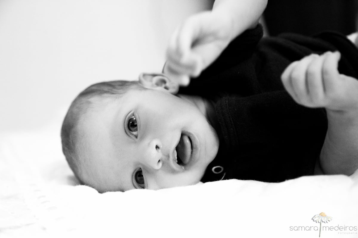 Bebê deitada sorrindo, foto preto e branca