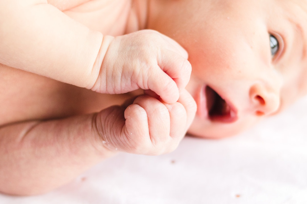 bebê bocejando com mãos juntas e boca aberta