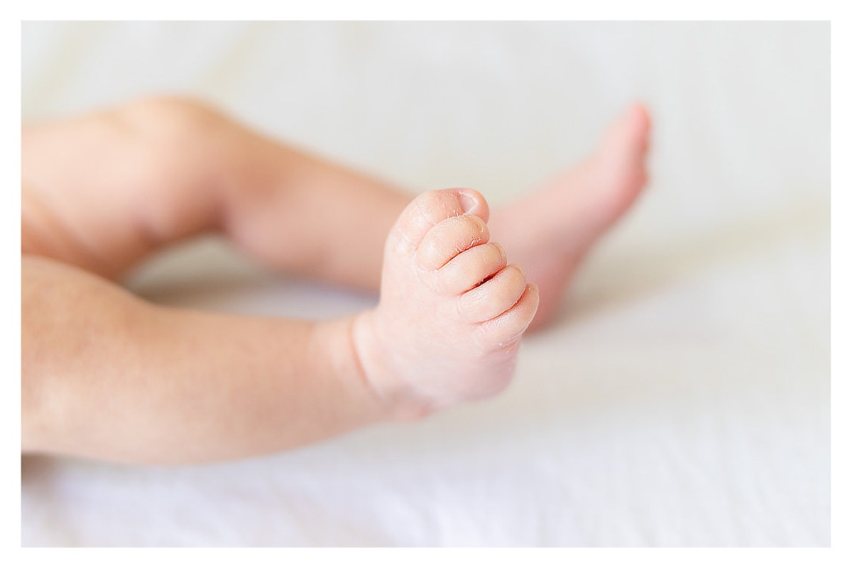 detalhes dos pés de bebê recém nascido, durante a sessão de fotos de newborn lifestyle em Curitiba, do fotógrafo infantil e de família Rapha Luna