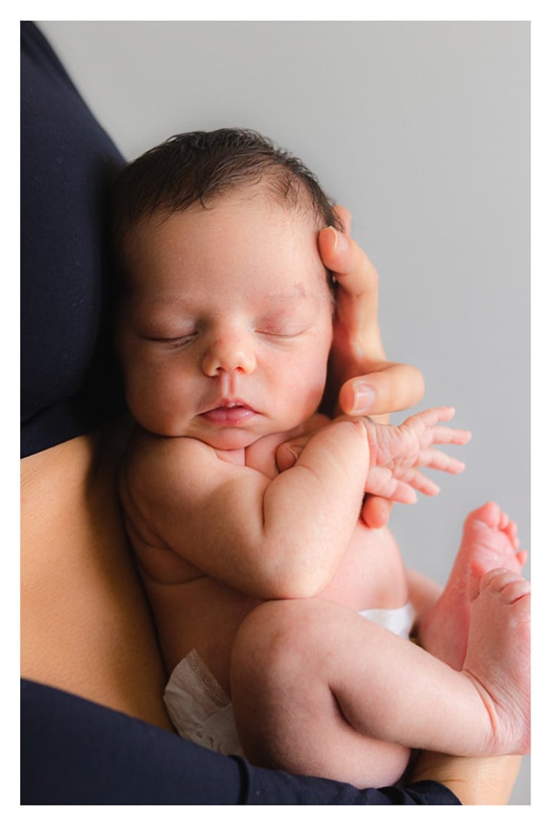 bebê recém nascida dormindo de olhos fechados no colo da mãe durante a sessão de fotos de newborn lifestyle em Curitiba, do fotógrafo infantil e de família Rapha Luna
