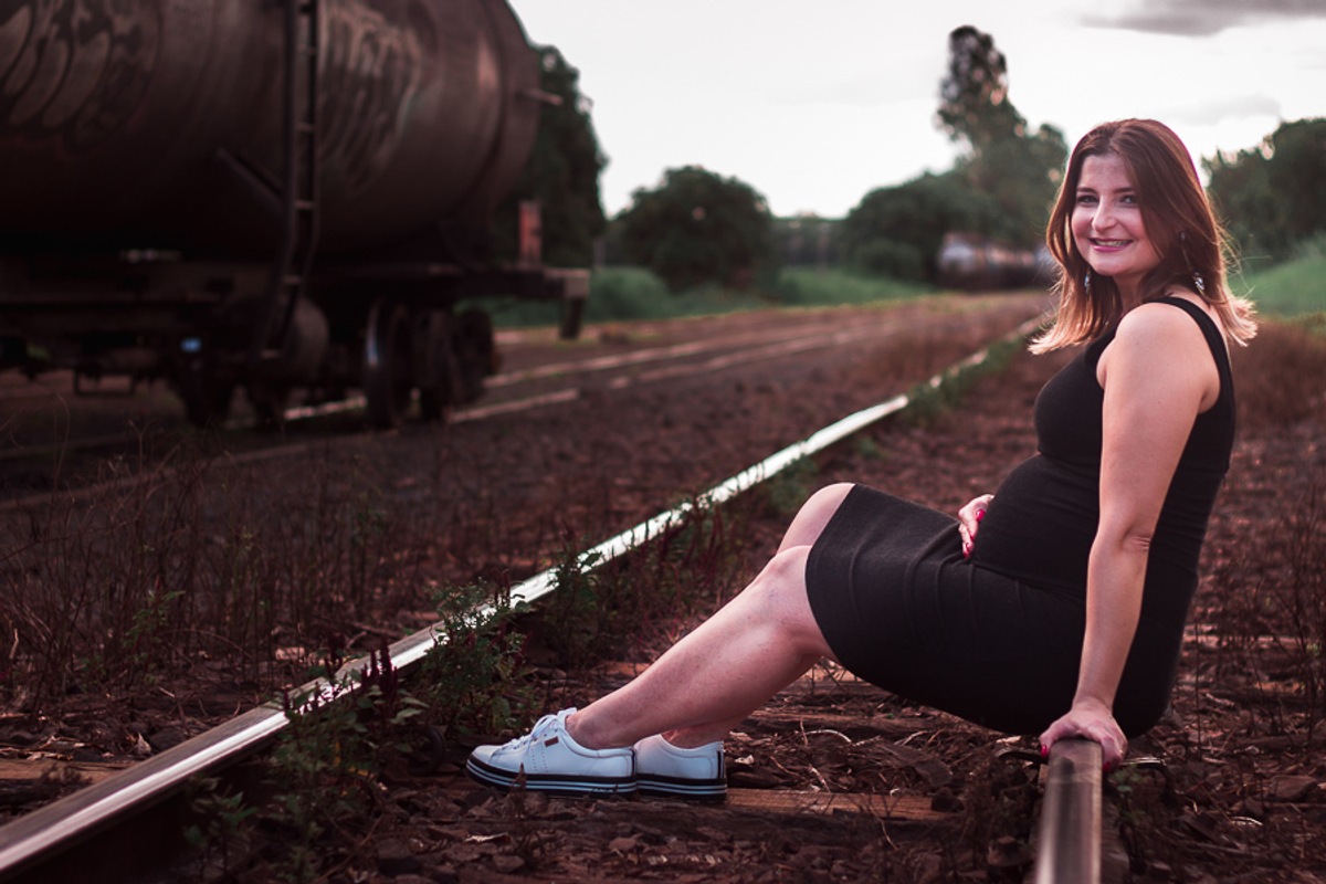 Fotografia de uma Gestante sentada na linhda do trem