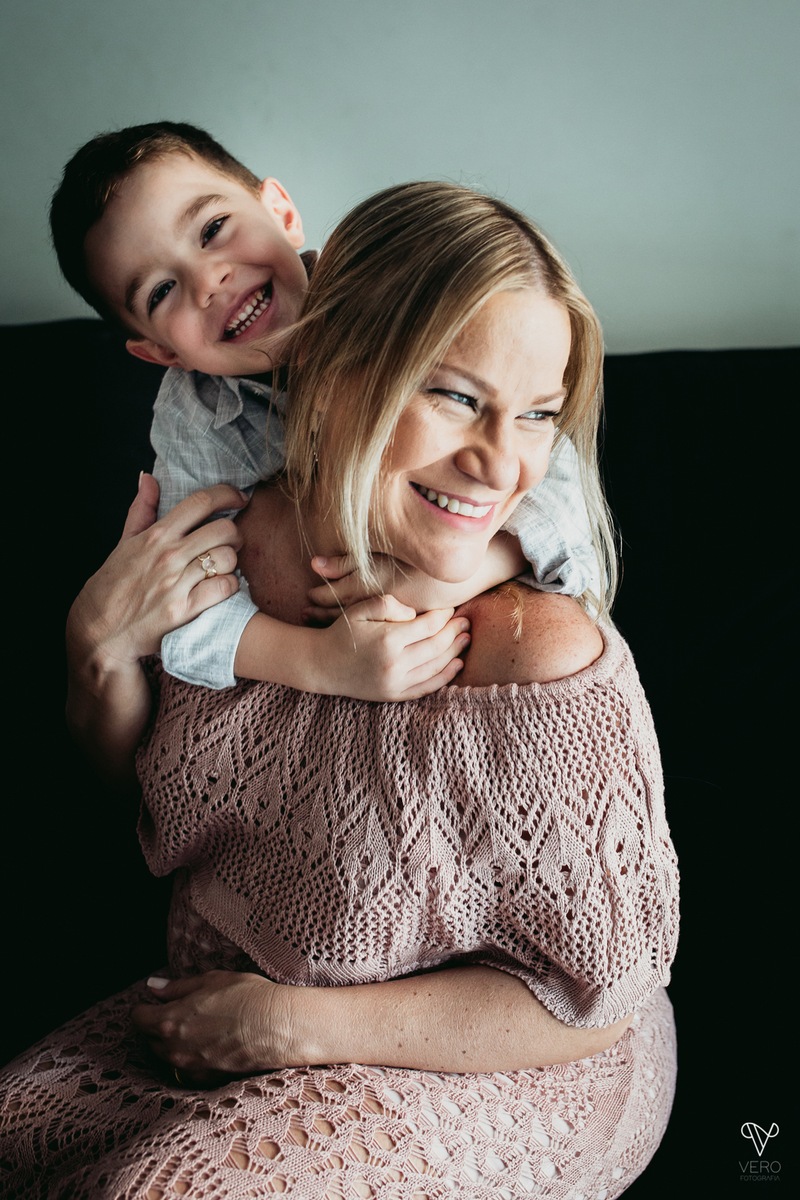 Filho abraça a mãe gestante no sofá