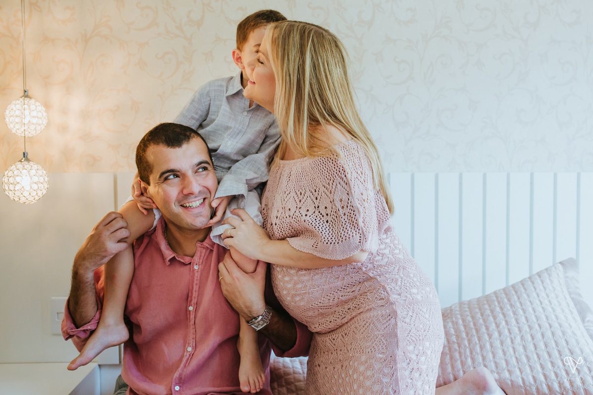 Pai, Mãe e filho se reunem na cama. Criança beija os pais