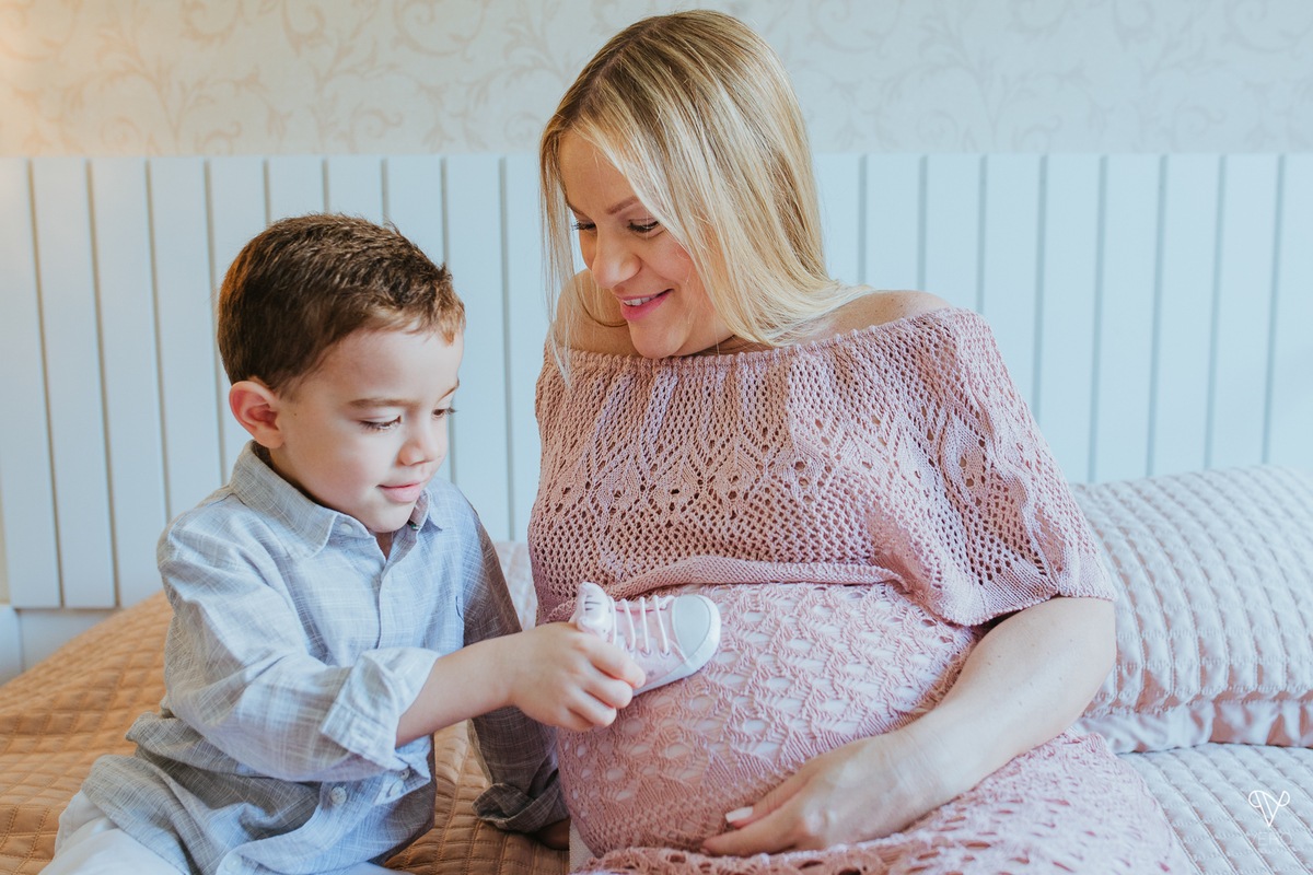 Mãe e filho brincam com sapato de bebê da irmã que vai nascer