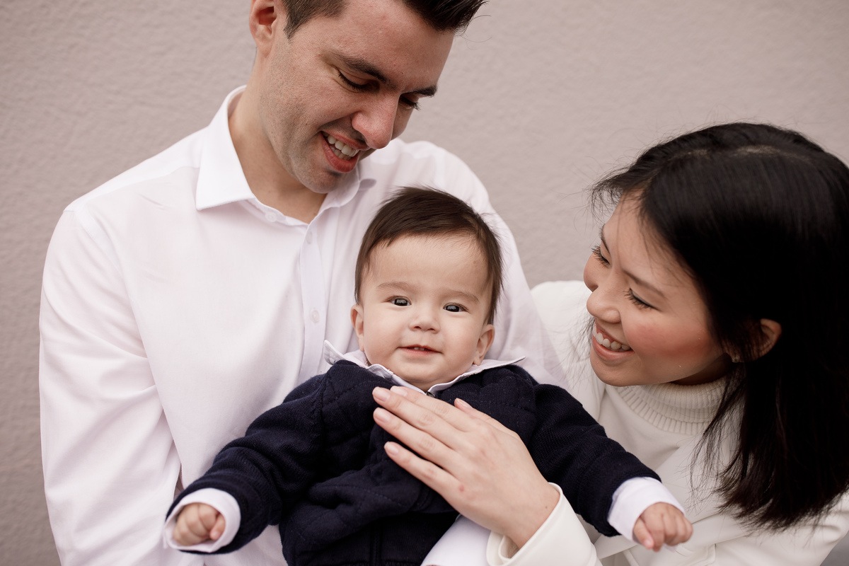 fotografia de família batismo de bebê japonês com roupa azul marinha e branca mãe e pai sorrindo e criança olhando para câmera fotos por ale carnieri cobertura fotográfica de eventos