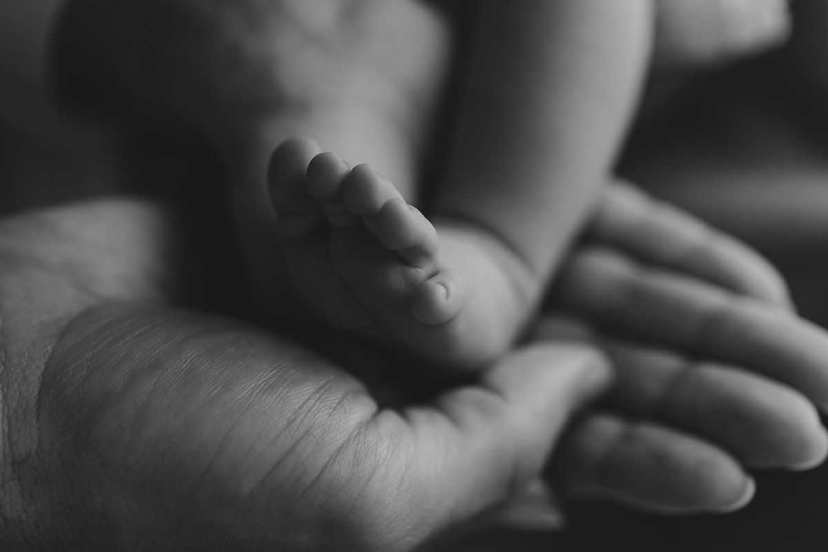 Pé do recém-nascido na mão da mãe, detalhe em preto e branco