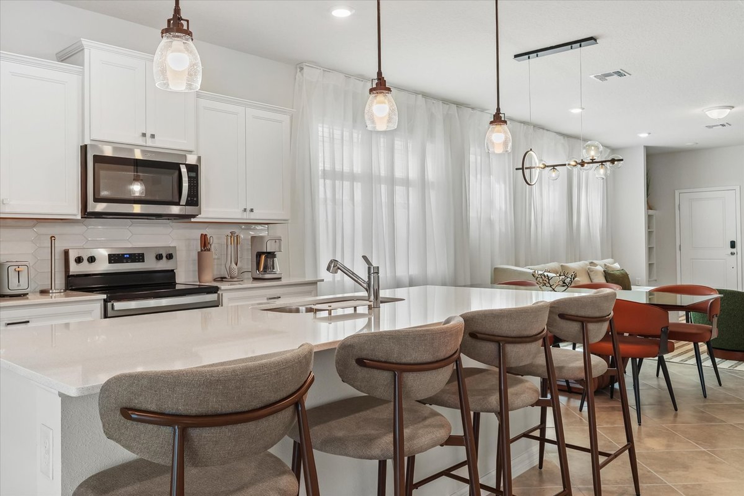 White kitchen island and seating in a Windsor Cay vacation home, photographed by Magic Lens.