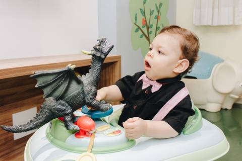 criança brincando com dragão no andador engraçado'
