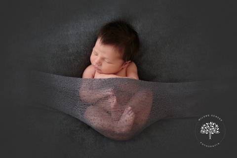 recém nascido cabeludo dormindo com fundo cinza'
