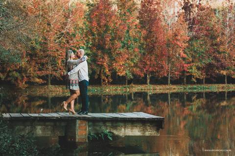 Casal se abraçando na ponte em cima do lago'