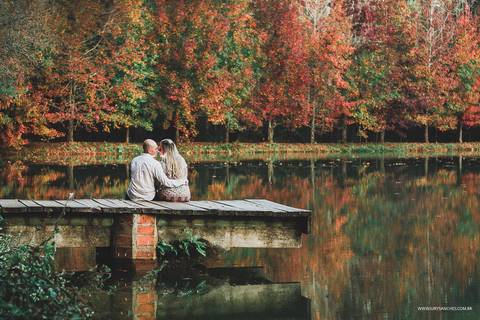 Casal abraçados na ponte em cima do lago'