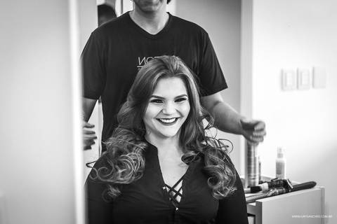 Menina se olhando no espelho e rindo durante seu making off no airton cabeileireiros'