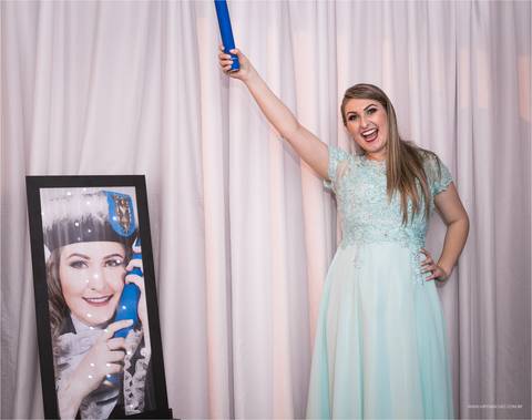 formanda comemorando ao lado de seu quadro de formatura'