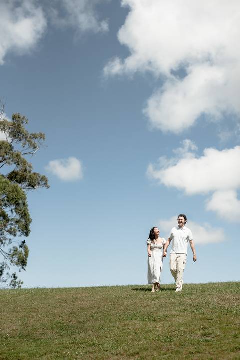 Cindy and Ryan walking across a wide lawn under an overcast sky after the proposal at Palácio de Monserrate, Sintra'
