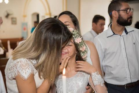 Mãe beijando filha que acabou de ser batizada'