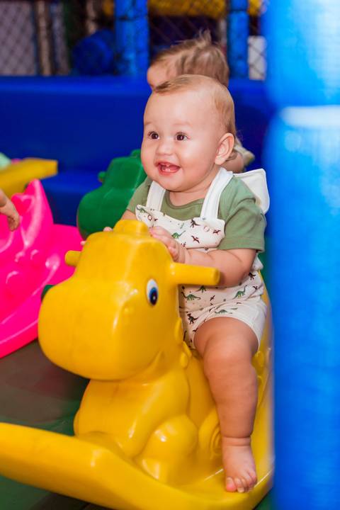 Gustavo se divertindo em um brinquedo amarelo no espaço infantil durante a comemoração do seu primeiro aniversário no Rafa Eventos, em Tatuí.'