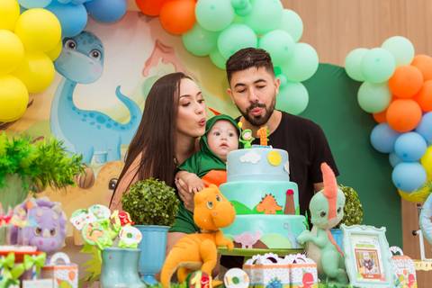 Momento do parabéns de Gustavo, com seus pais soprando a velinha do bolo decorado com dinossauros na festa de 1 ano em Tatuí.'