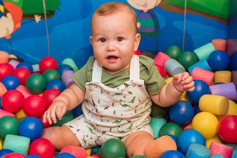 Gustavo se divertindo na piscina de bolinhas, cercado de cores e brincadeiras durante seu aniversário de 1 ano.'