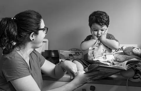 Fotografia de família com criança lendo com a mãe'