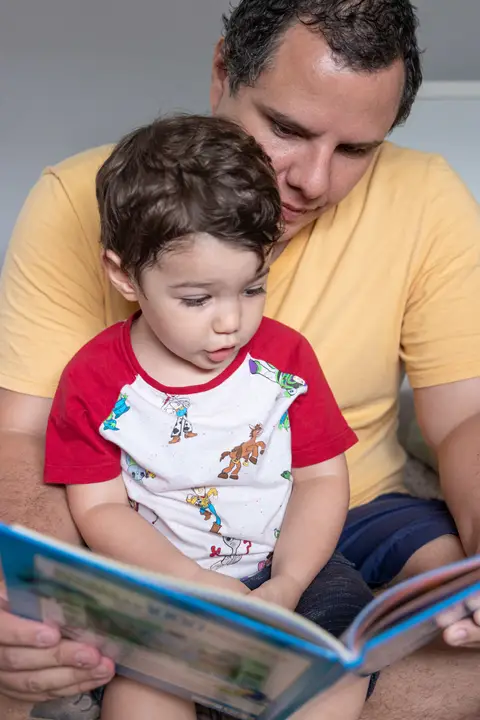 Fotografia de família com criança lendo com o pai'