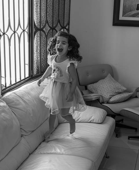 Fotografia de família com criança pulando no sofá'