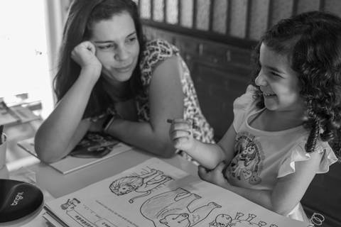 Fotografia de família com criança fazendo dever de casa com a mãe'