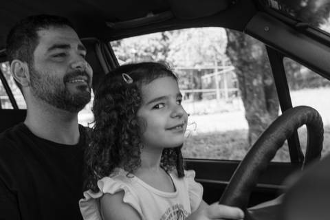 Fotografia de família com criança brincando com o pai no carro'
