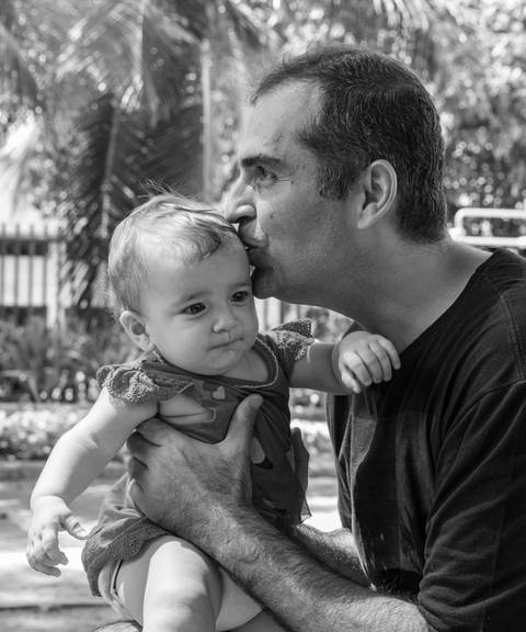 Fotografia de família com pai beijando a cabeça da filha'