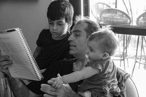 Fotografia de família com pai lendo para os filhos'