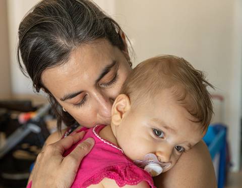 Fotografia de família com mãe beijando a filhano colo'