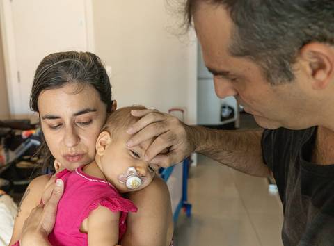 Fotografia de família com pais colocando bebê pra dormir'