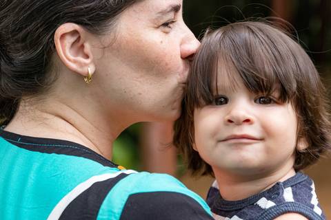 Fotografia de família com mãe beijando a cabeça do filho'