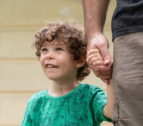 Fotografia de família com menino segurando a mão do pai'